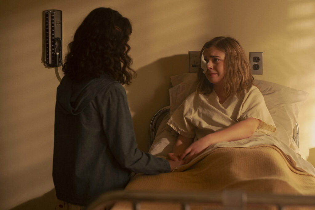 Marge is sitting in a bed. She's talking to Lilly, who's next to the bed