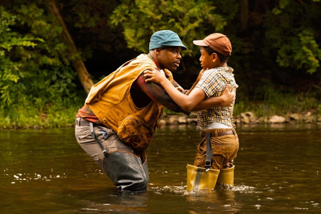 It: Welcome to Derry - Leroy and Will are standing in a river, Leroy is facing Will and holding him